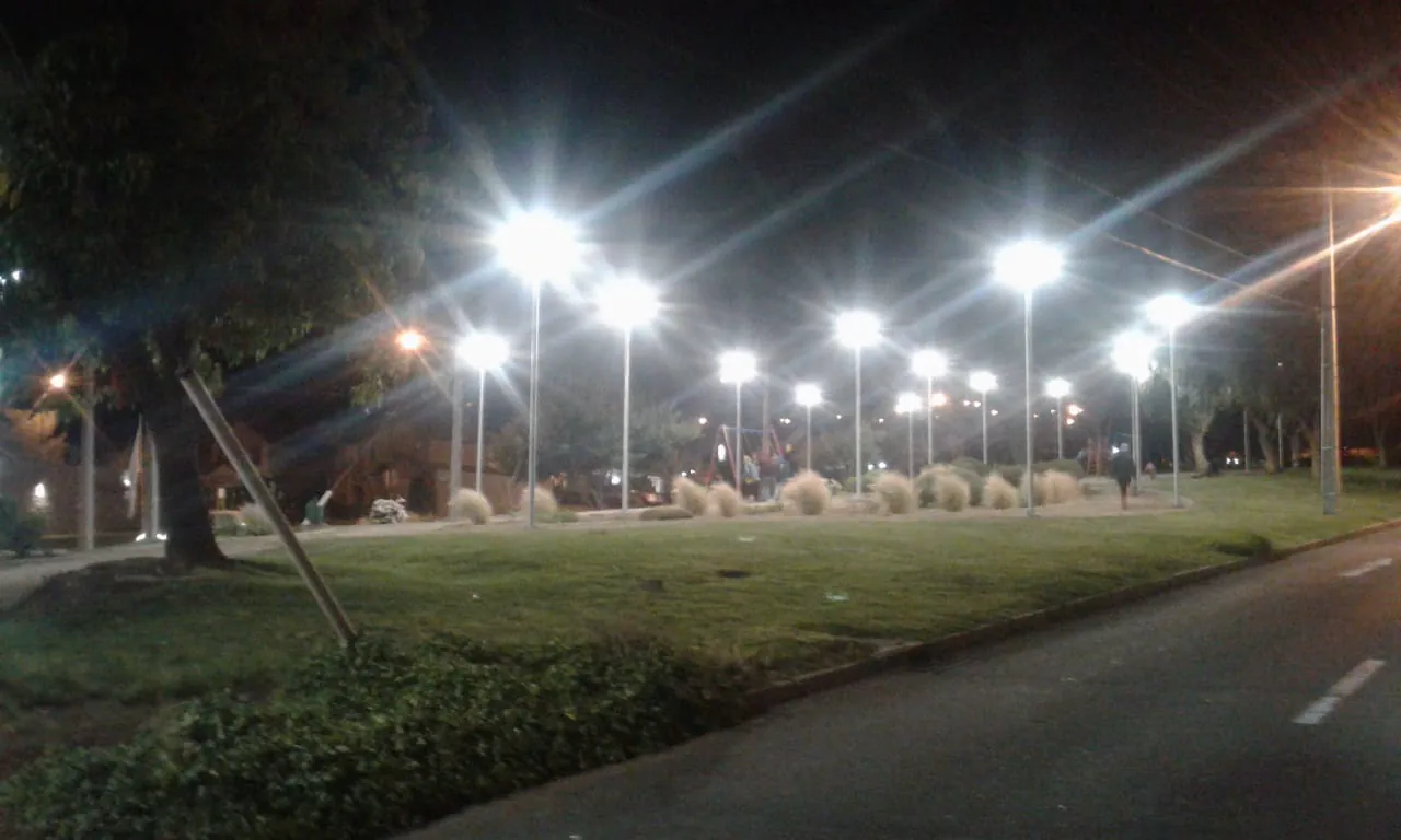 Avenida y plaza iluminadas de noche por luminarias LED de alumbrado público