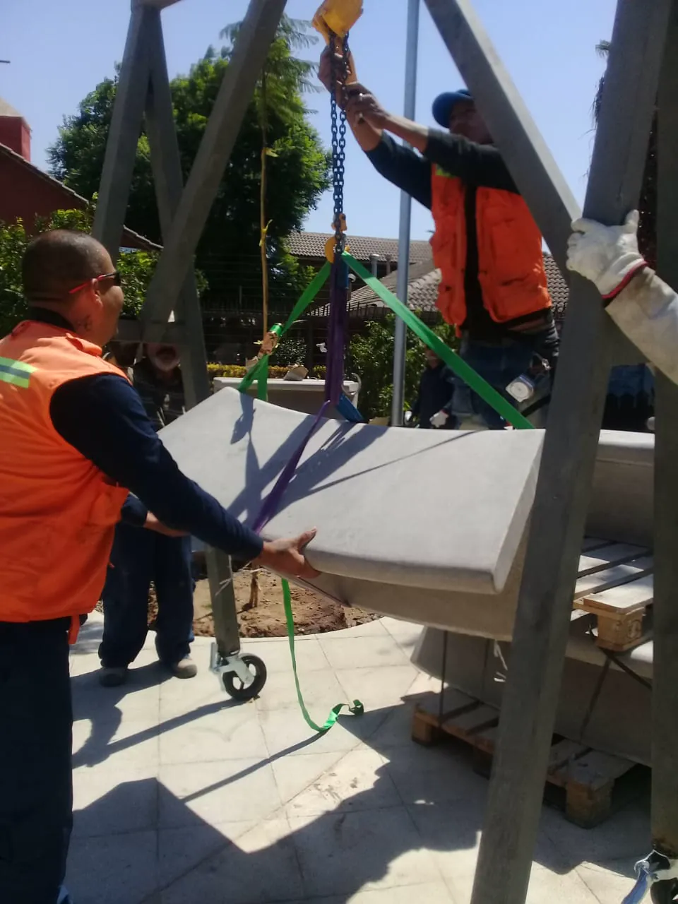 Cuadrilla de EDT izando una pieza de hormigón con tecle y eslingas en una obra